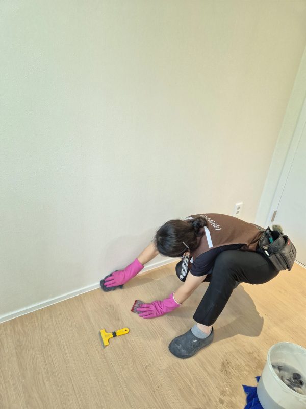 벽면 걸레받이 모서리를 도구로 닦는 작업자의 모습