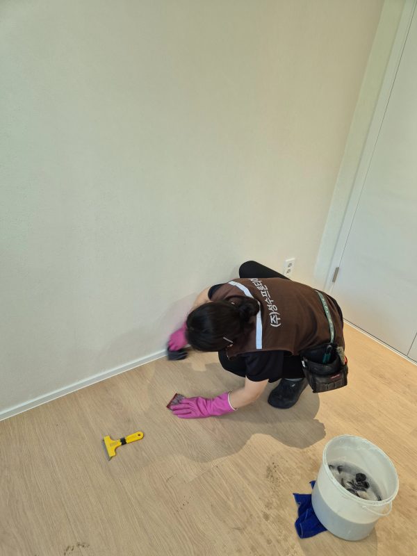 벽면 걸레받이 모서리를 정리하는 작업자의 뒷모습