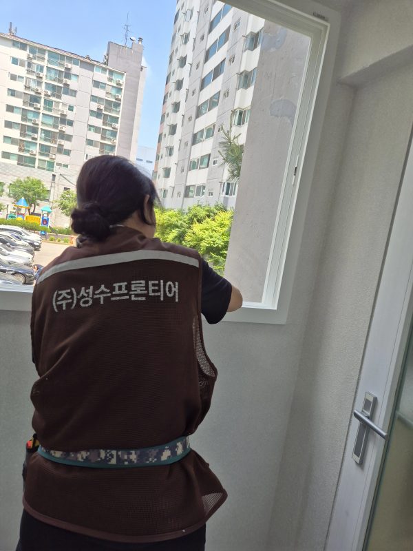창가에서 창틀 표면을 점검하는 작업자의 뒷모습